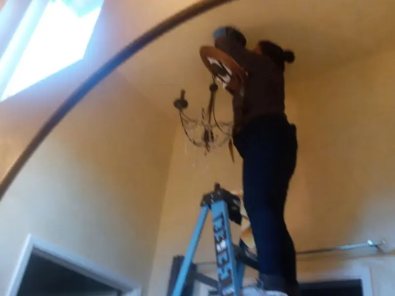 Electrician installing a chandelier in a Providence residence